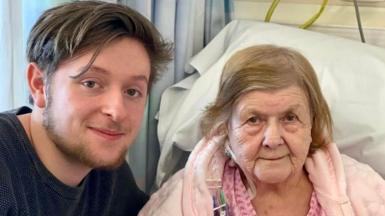 Tristan Essex on the left next to Jessie Stockdale who is in a hospital bed wearing a pink dressing gown.