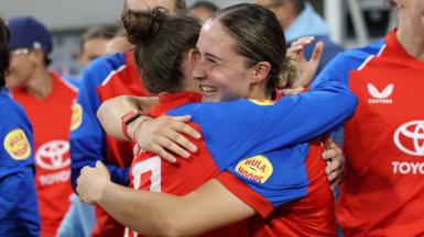 Alice Capsey is hugged by a team-mate