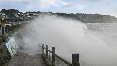 A wave crashing over a sea wall 