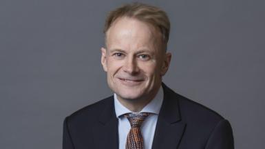 Richard Scolyer smiles at the camera, wearing a suit and tie