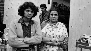 People gather outside a shop with boarded up windows on The Broadway in Southall following rioting, picture date 4 July 1981