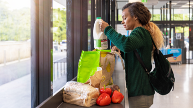 A woman packing groceries into a shopping bag at the supermarket