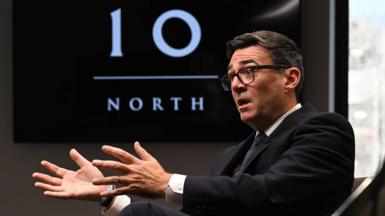 Andy Burnham seated in a dark suit and tie in front of a Number 10 North sign