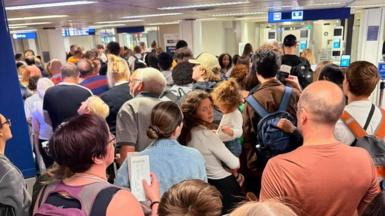 A large queue of people waiting in an airport.