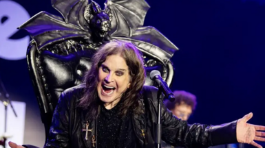 Ozzy Osbourne, dressed in a black leather jacked sat on a black throne with a microphone in front of him