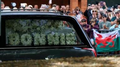 Crowds line the street as the funeral cortege passes.