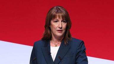 Rachel Reeves, a white woman in her 40s. She has brown, shoulder length hair with a fringe. She is standing in front of a red and white backdrop, and the lecturn in front of her has a red sign that says "renew Britain".