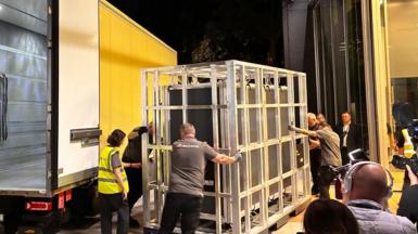 The tapestry arring in a crate being loaded from a yellow van in the middle of the night