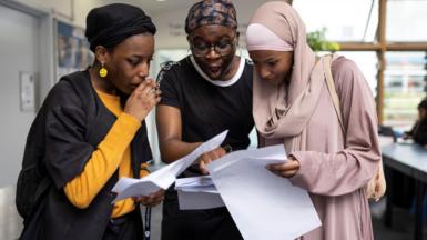 Three students look at their A-level results in shock. 