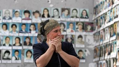 A woman weeps as she looks at photos of the victims killed in the school sports hall in Beslan