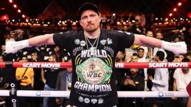 Oleksandr Usyk with his arms outstretched and 'Egypt 23.5.26' written on his right hand and 'winner' written on his left hand