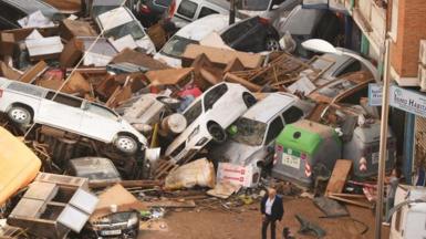 Cars are piled in the street with other debris after flash floods hit parts of southern Spain