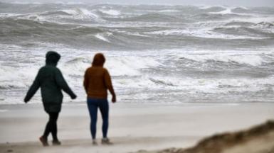 Two women walk on a beach 