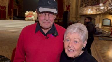Ron Hill, 82, and his wife Marilyn, 80, at the Tower Ballroom. Ron wears a red jumper and black cap and Marilyn is dressed in black. 