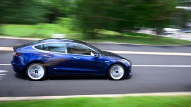 A Tesla vehicle drives off the lot at the company's store in Warminster, Pennsylvania, US, on Tuesday, July 22, 2025. 