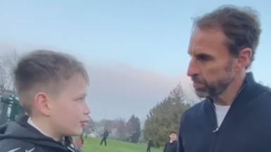 A side shot of Jacob interviewing Gareth Southgate in a park. They are looking at one another and viewed from side on.