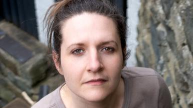 Ruth has dark hair and is looking directly at the camera.
