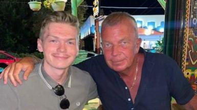 A man and his son smiling at the camera