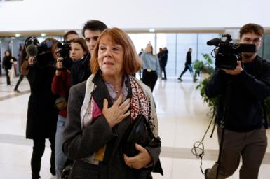 Gisele Pelicot walking through the halfway of a courthouse followed by cameras.