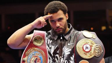 Moses Itauma salutes the camera with his belts around his shoulders