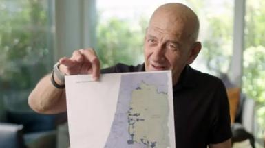 Former Israeli Prime Minister Ehud Olmert holding up his proposed map of Israeli and Palestinian states, as part of a two-state solution