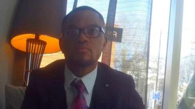 Undercover footage of a man in a suit, wearing glasses, in a hotel lobby.