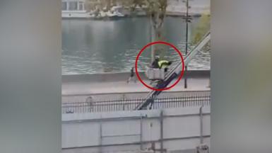 Two thieves dressed in dark clothing with one wearing a yellow hi-viz vest descend on a ladder 