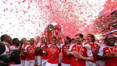 Arsenal captain Martin Odegaard lifts the Premier League trophy surrounded by his team-mates