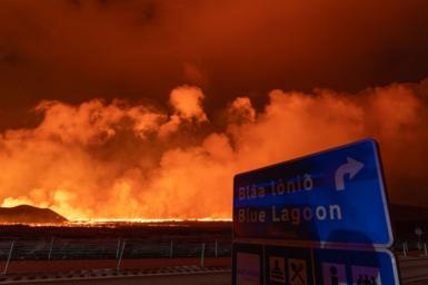 A road sign for Blue Lagoon with flames in background 