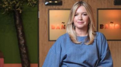 Diane Hutchinson, played by Alex Fletcher, is wearing a denim dress and smiling at the camera.