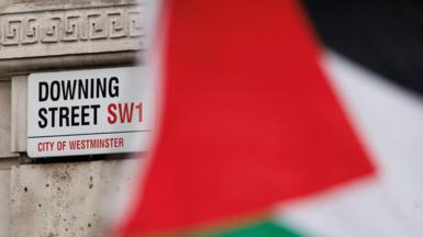  A Palestinian flag flies in front of a road sign reading Downing Street, SW1
