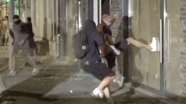 A man wearing white trainers kicks a window of an office belonging to Serbia's ruling party.