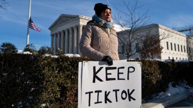 A woman holding a sign reading 'Keep TikTok' standing in cold-weather clothes outside the Supreme Court in the US.