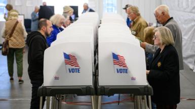 US voters make selections at a double row of voting booths