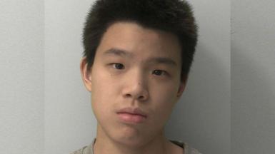 A mugshot of a boy with short black hair looking expressionless.