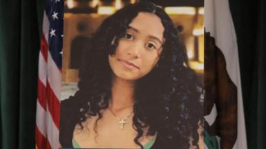 A photo of Celeste Rivas Hernandez is displayed on an easel in front of the US and California flags onstage at a media conference announcing charges against US singer David Anthony Burke, who is known professionally as D4vd.