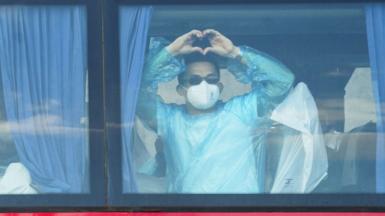 A person makes a heart shape with his hands while riding a bus transporting passengers from the MV Hondius cruise ship to Tenerife South Airport from the Port of Granadilla de Abona in Tenerife, Spain, 11 May 2026.