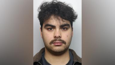 Kyran Smith mugshot. He has dark hair and dark stubble.