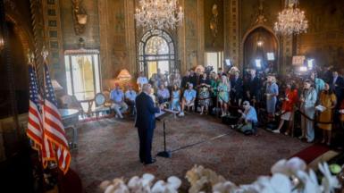 Donald Trump stands at a podium before a large group of reporters at his Mar-a-Lago estate in Florida 