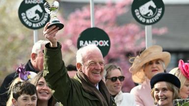 Willie Mullins smiling and holding a trophy in the air