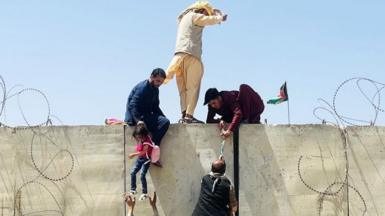 Afghans scaling a wall to access Kabul airport during the evacuation in 2021