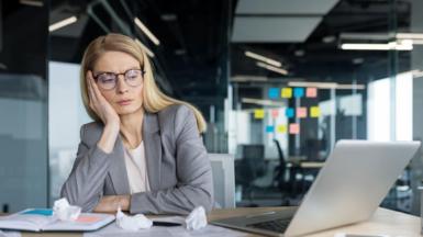Tired and disappointed businesswoman sitting near documents and scraps of paper.