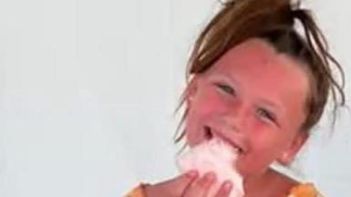 A child eating candy floss and smiling.