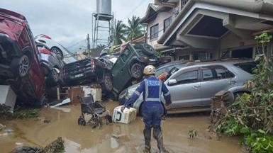 A rescuer walks past piled up cars washed away by floods at the height of Typhoon Kalmaegi in Cebu City, in the central Philippines, on 4 November 2025. 