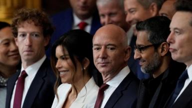 From left to right: Meta CEO Mark Zuckerberg wearing a navy suit, red neck tie and white dress shirt; Lauren Sanchez, wife of Amazon founder and former CEO Jeff Bezos, wearing a white blazer; Jeff Bezos, in a navy suit, red neck tie and white dress shirt; Google CEO Sundar Pichai, in an all black coat, shirt and tie.