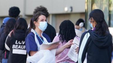 Students wait in line at the entrance to the sports hall at University of Kent campus in Canterbury for where the rollout of a meningitis B vaccine to about 5,000 students has begun