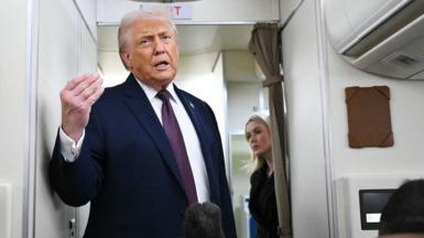 Donald Trump talking to press on Air Force One he is wearing a navy blue suit