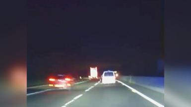 White van drives down A421 at night at speed overtaking a red car and approaching a lorry