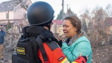 A handout photo released by the press service of the State Emergency Service (SES) of Ukraine shows a Ukrainian psychologist assisting a woman near the site of an air strike in Odesa, southwestern Ukraine, 17 November 2024.