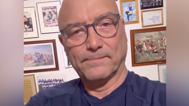 Man with glasses in navy T-shirt looks at camera